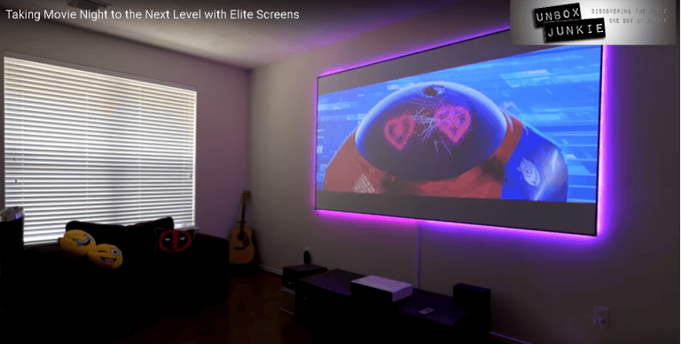 Large fixed-frame projection screen displaying colorful movie scene in a home theater.