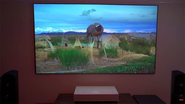 Projection screen displaying scenic landscape with a vintage camera and rural huts.