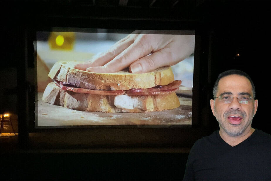 Projection screen displaying a close-up of a sandwich being made.