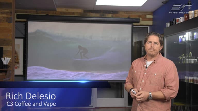 Indoor home theater with projection screen and a man standing nearby.