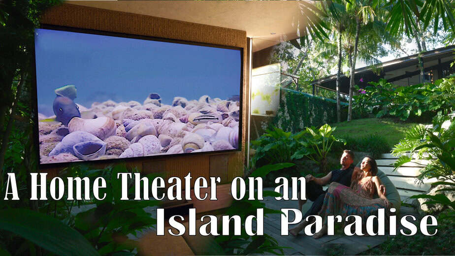 Large projection screen displaying a beach scene in a tropical outdoor setting.