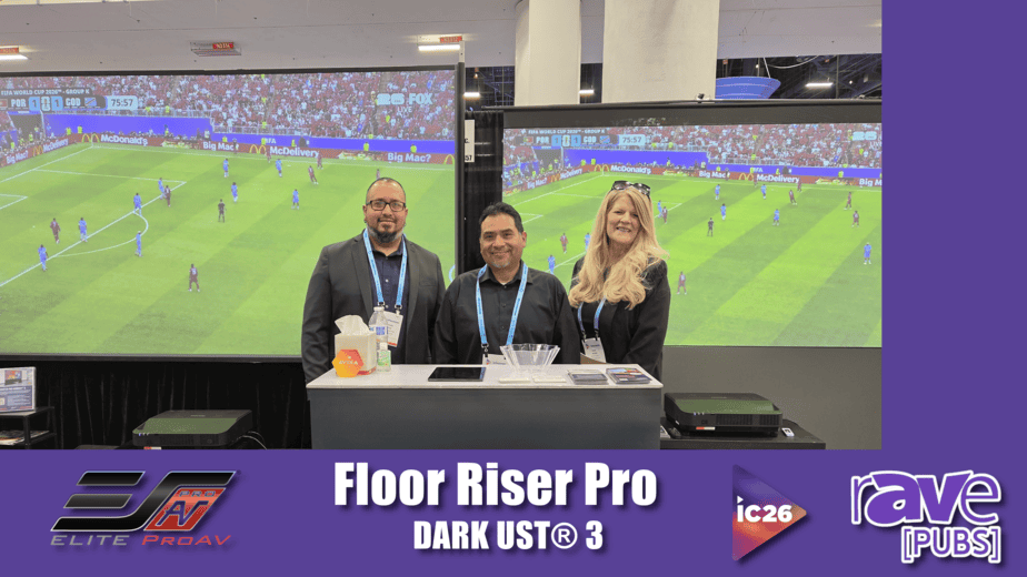 Large projection screens displaying a soccer game at a tech event.